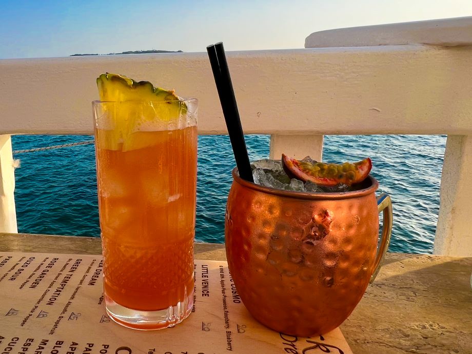 Two colorful cocktails by water