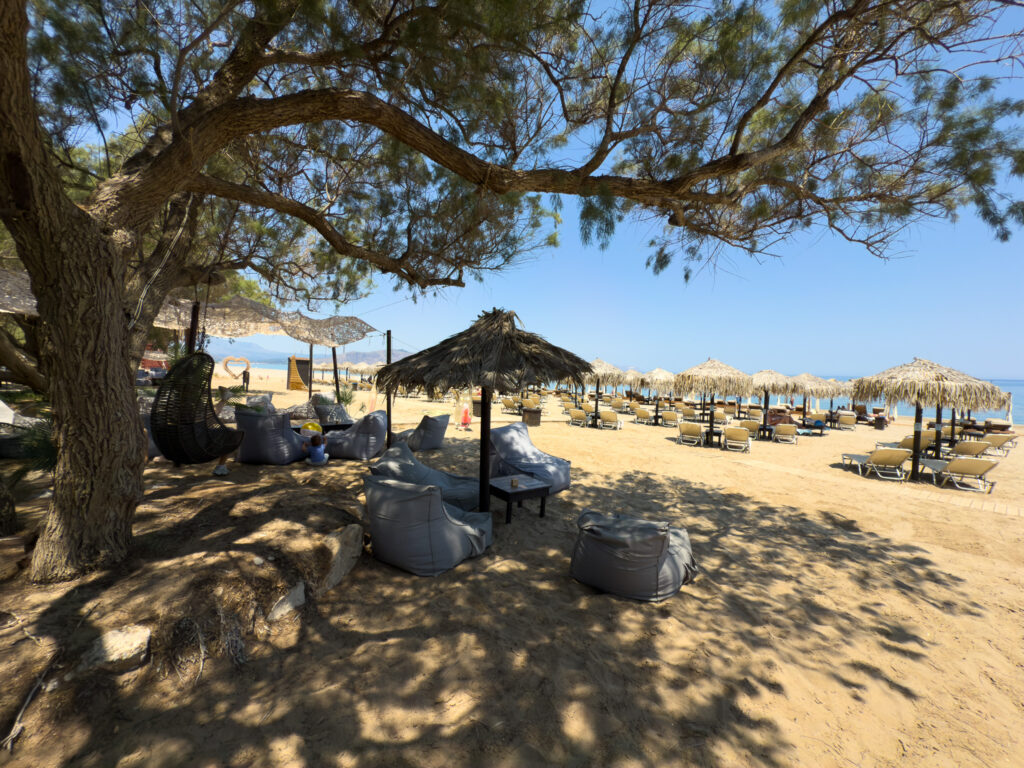 View of sun loungers through trees at Sirokos Taverna at Episkopi Beach in Crete Greece