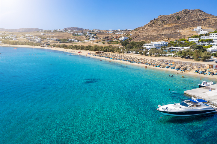 a beach with a boat and chairs and a sandy beach Aerial view to the popular Kalafatis Beach on Mykonos