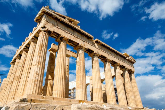 a stone structure with pillars with Parthenon in the background