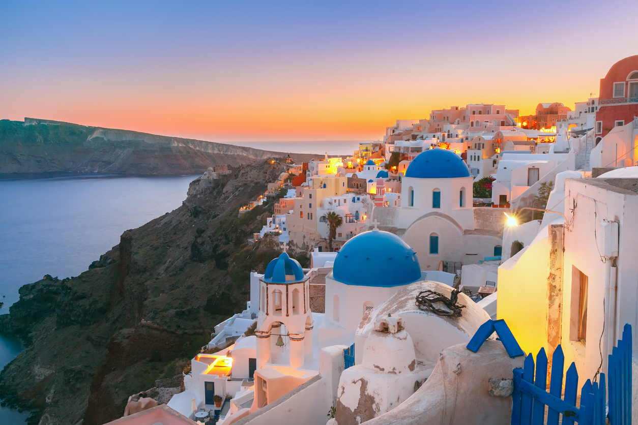 Santorini Caldera blue domes and white buildings on a cliff at sunset