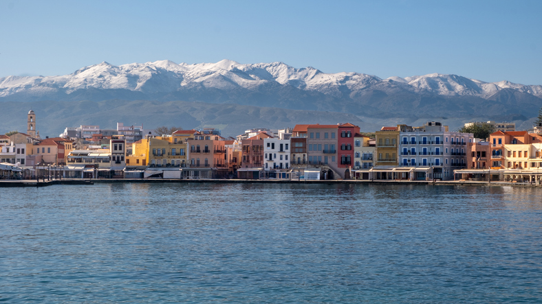 a city next to water with mountains in the background