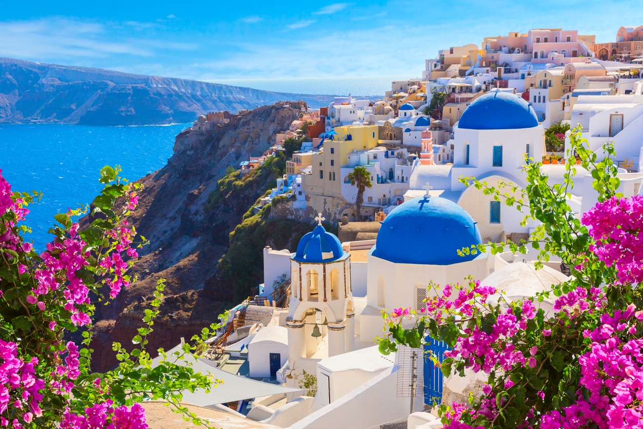 a white buildings with blue domes on a cliff Santorini island, Greece. Oia town traditional white houses and churches with blue domes over the Caldera, Aegean sea.