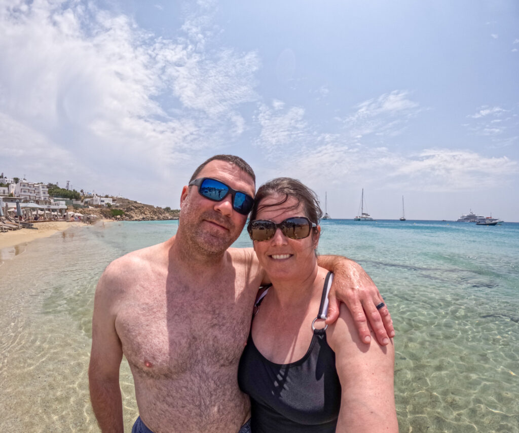 a man and woman standing in the water at Platis Gialos Beach Mykonos Greece