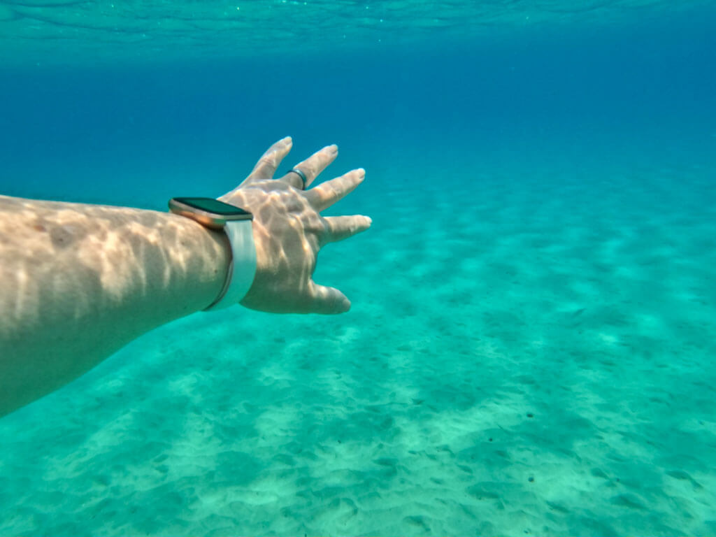 Hand reaching into clear blue water in Mykonos